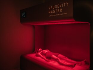 Person, die Rotlichttherapie macht und unter rotem Licht liegt