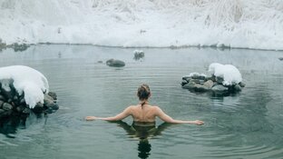 Frau badet in Wasser umgeben von Eis und Schnee