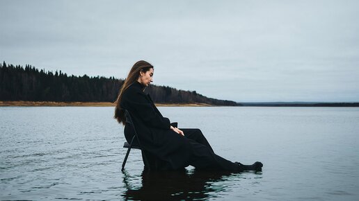 Donna seduta su una sedia pieghevole nel lago che non sembra felice