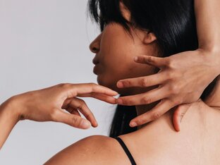 Frau mit schwarzen Haaren und glatter Haut mit ihren Händen an ihrem Kopf