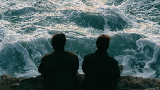 Zwei Personen sitzen am Meer