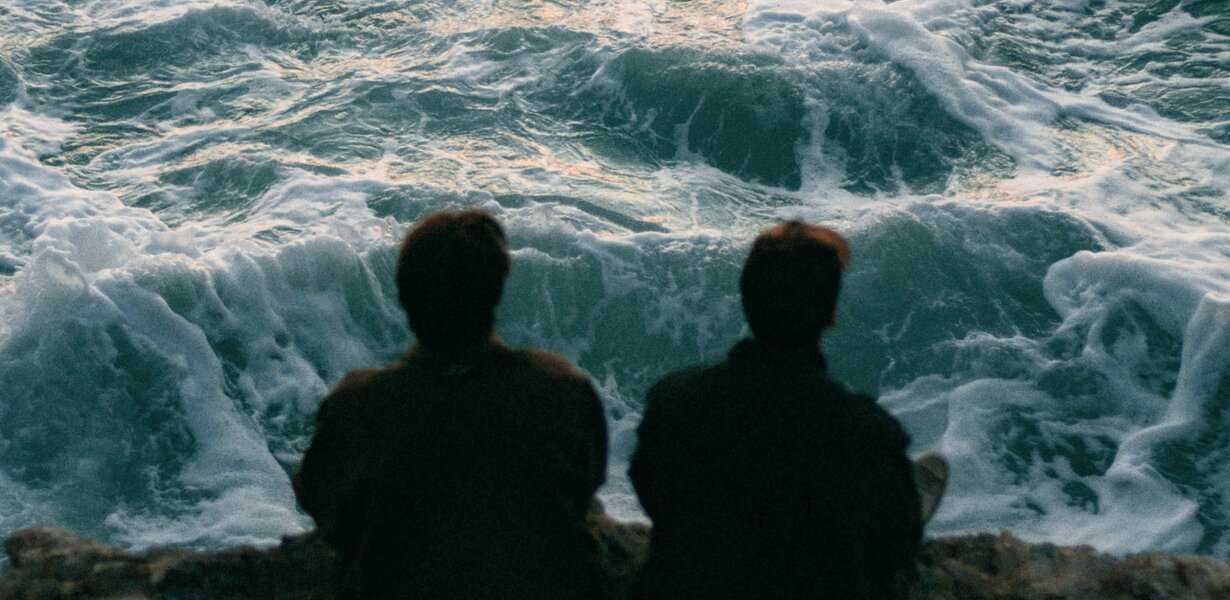 Zwei Personen sitzen am Meer