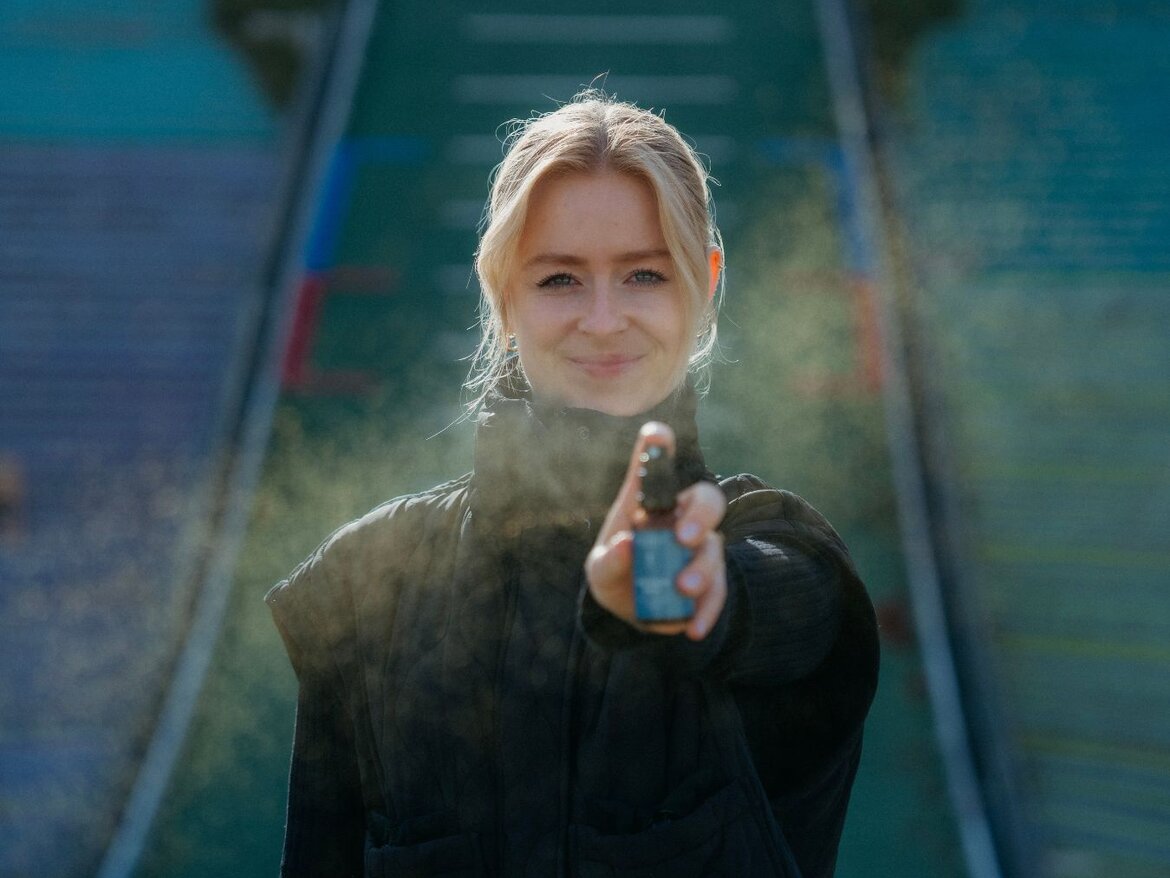 Plava žena prska Mito Energy Spray, sa skakaonicom u pozadini